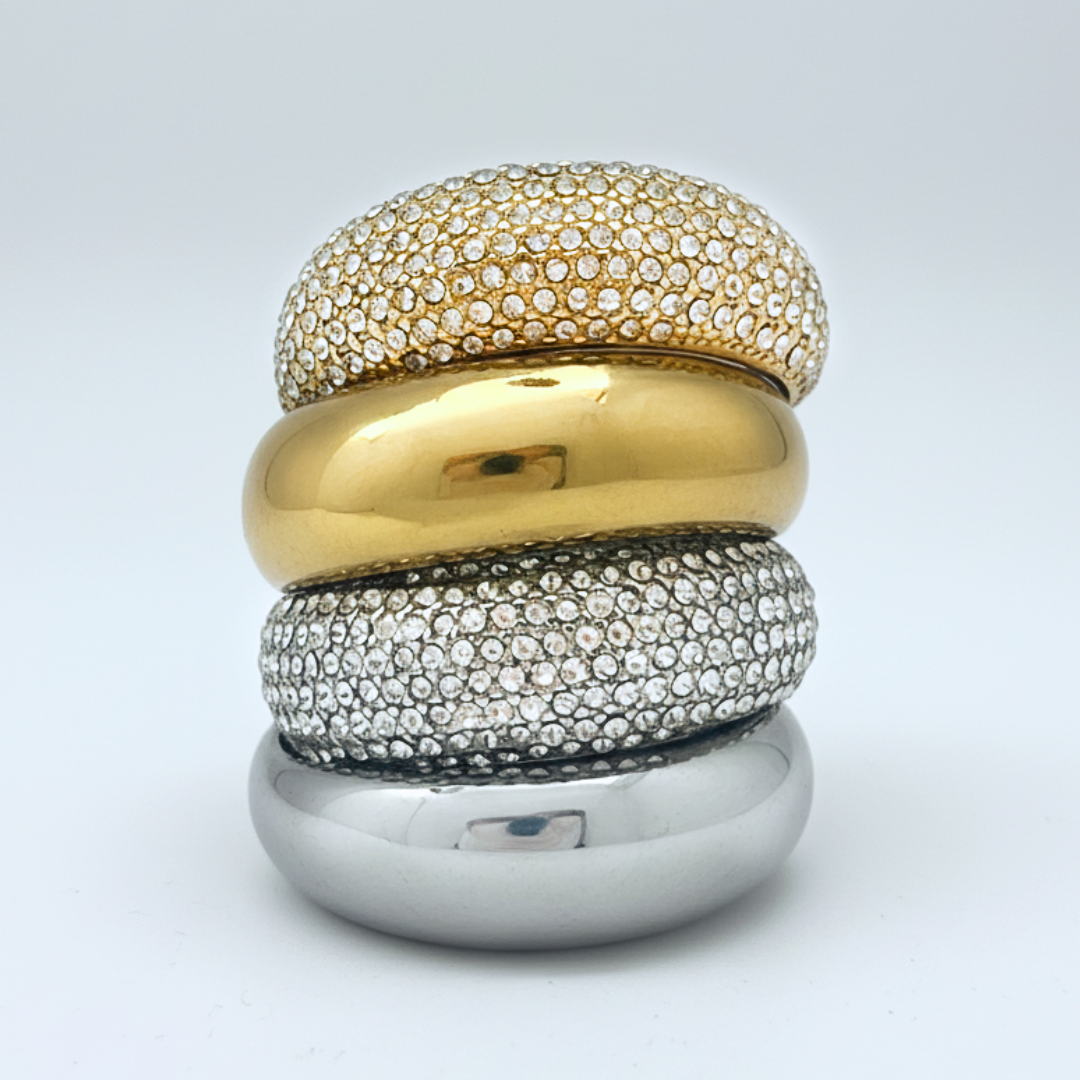 Stack of three gold, silver, and gold rings on a light gray background