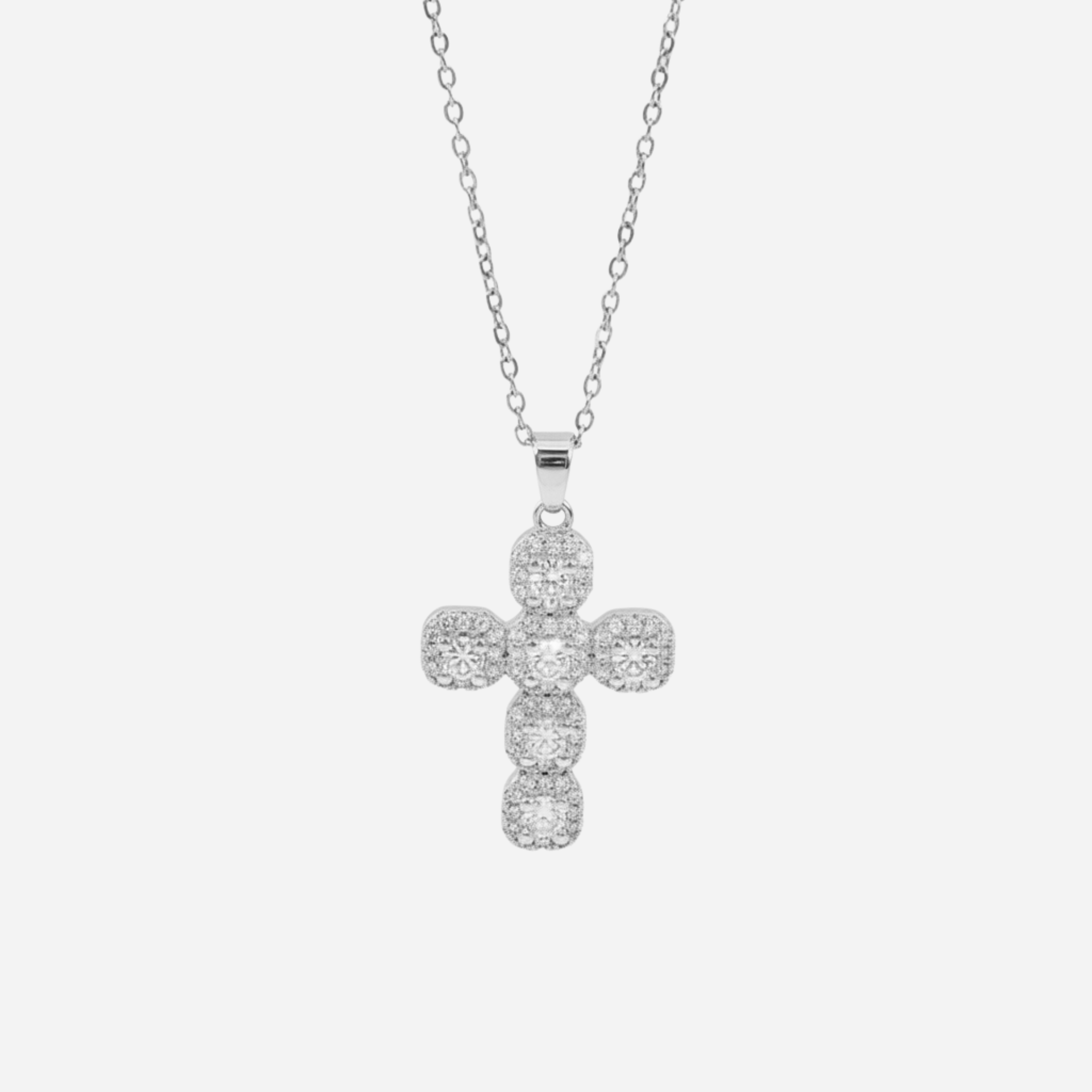 Silver cross pendant necklace on a light gray background