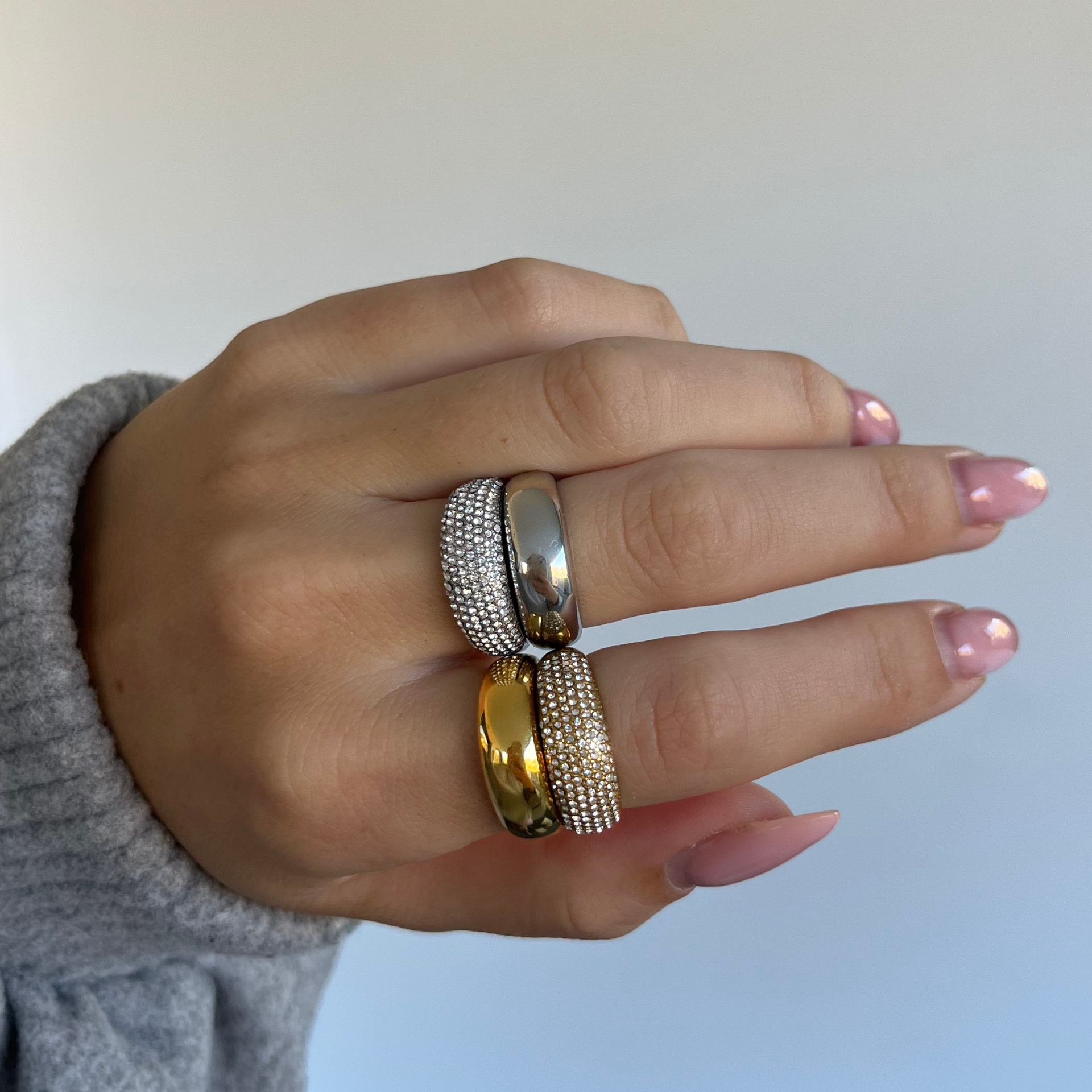 Hand wearing two rings with a light background