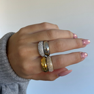 Hand wearing two rings with a light background